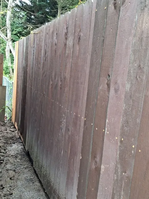 Close-set vertical wood boards form a continuous privacy fence along a narrow side passage.