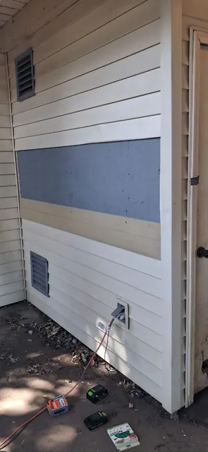 A horizontal gray-blue strip contrasts with light siding while the adjacent corner trim remains exposed.