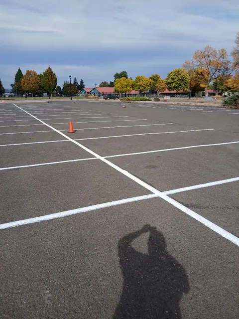 Bright white parking-space lines cross the asphalt, with cones still standing in the lot.