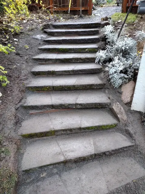A defined flight of garden steps leads toward the gate, with the surrounding soil still exposed.