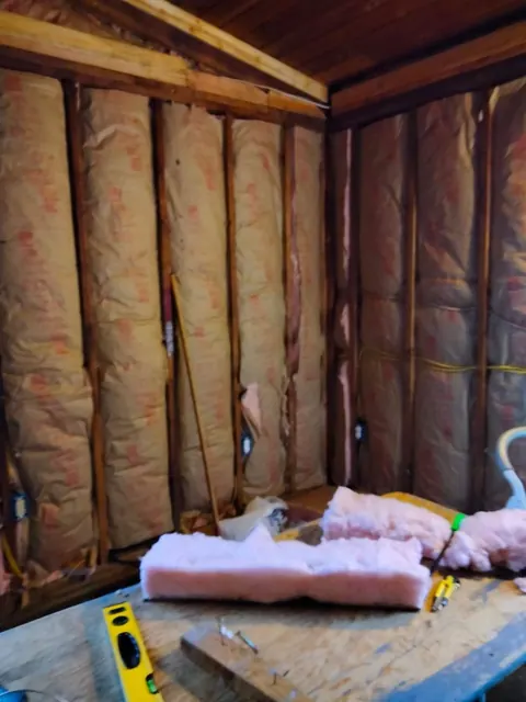 Exposed wall studs and insulation show an interior room during the wall-preparation stage.